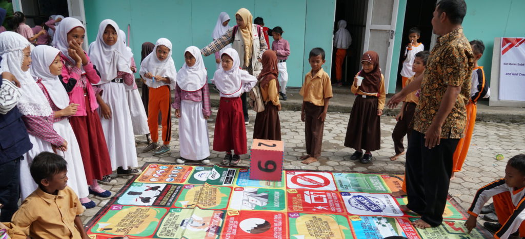 Lombok, Indonesia, 2019. 
School kits for the kids in Lombok island. Almost 6 months after Lombok  was struck by multiple earthquakes, many damaged schools have been rebuilt and repaired. Some schools still need time to be completely repaired or rebuilt. PMI staff and volunteers trained in pyschological support continue to visit children to help them cope with their fears following the series of earthquakes.  As well as distributing school kits, volunteers are actively  and creatively integrating care in their work, engaging children in games and role playing, while at the same time introducing best hygiene practices.