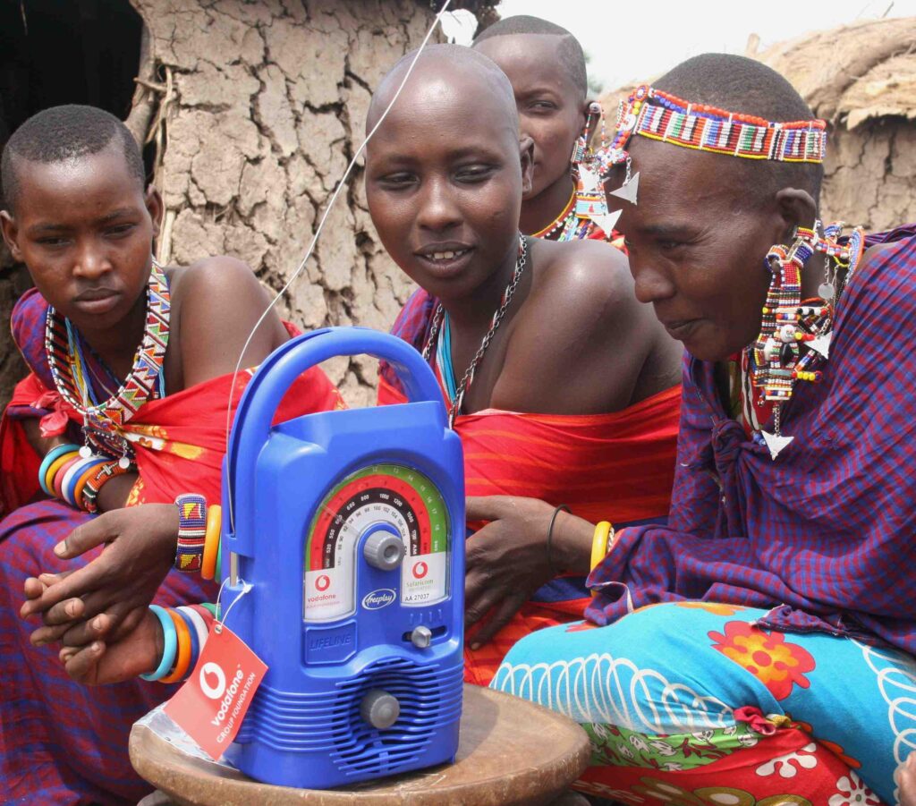 Three women from a Masai area of Kenya sitting around a solar-powered radio that is used as an early warning system