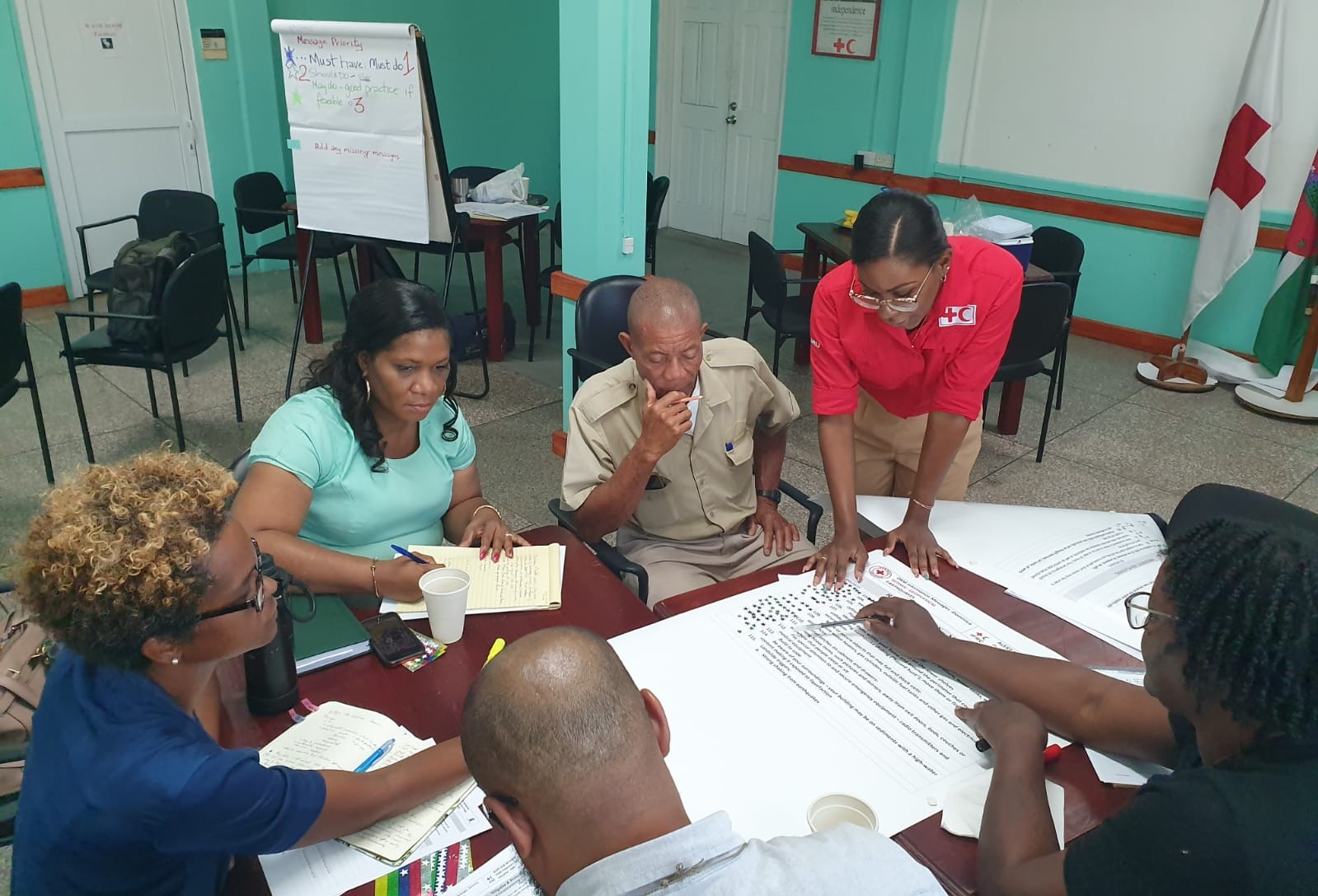 A group of individuals is gathered around a table, actively engaged in reviewing and discussing documents during a workshop.