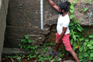 Marigot Community member demonstrates how to use river gauge.