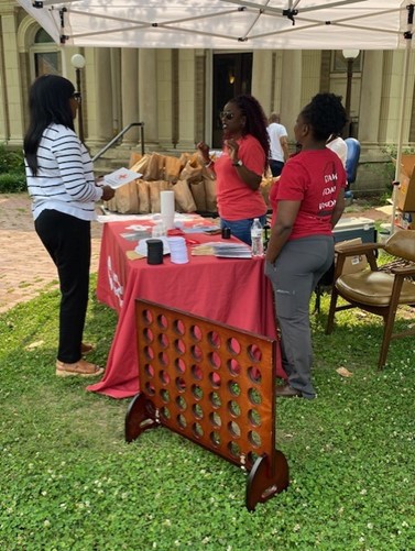 CAP team heat action day Dr. April Masha Jones and a team member stand at a Red Cross information table speaking with a visitor during an outdoor event.