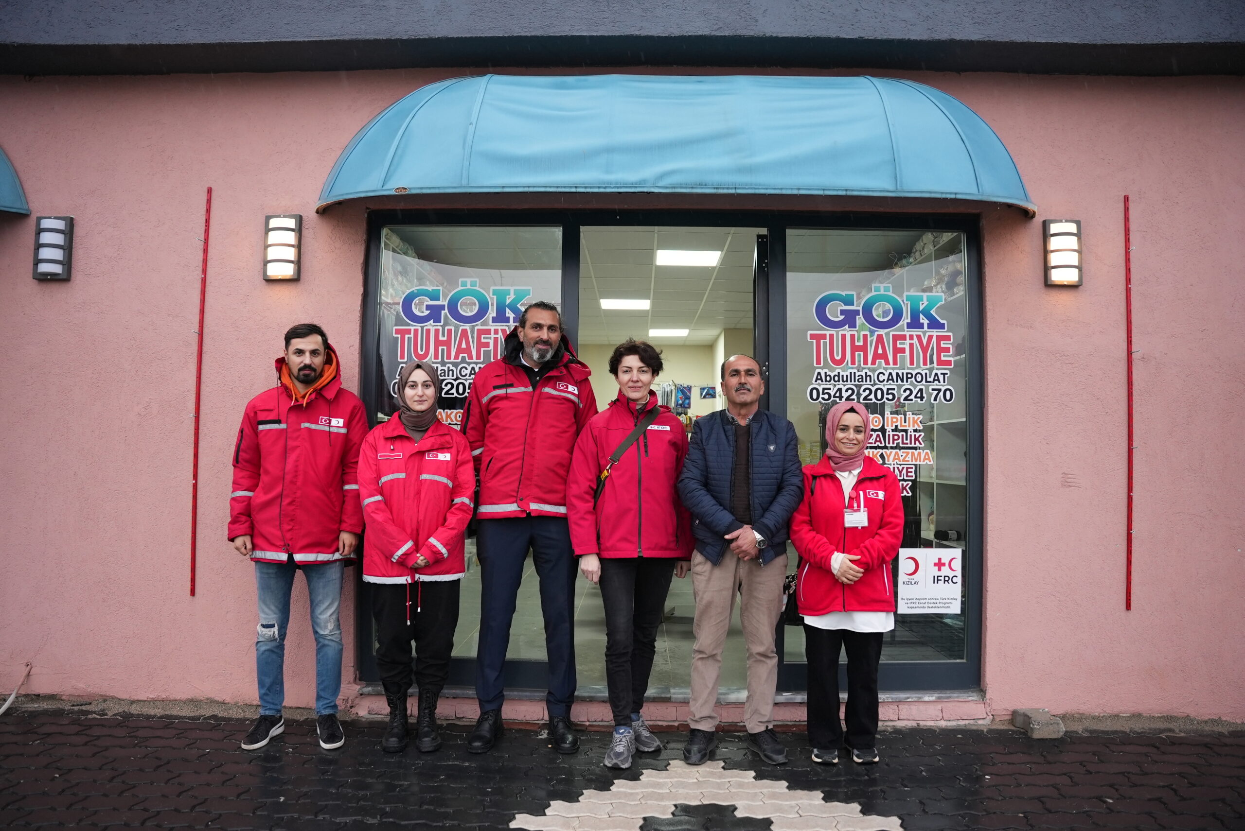 Store owner stands outside his store with RC volunteers. His store was supported by the Turkish Red Crescent’s livelihoods cash grant in cooperation with IFRC after his workplace was damaged in the earthquakes on February 6th, 2023