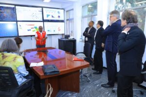 An Ethiopian Red Cross staff member in a red vest presents emergency response data on large screens to a group of visitors at an Emergency Operations Centre in Ethiopia.