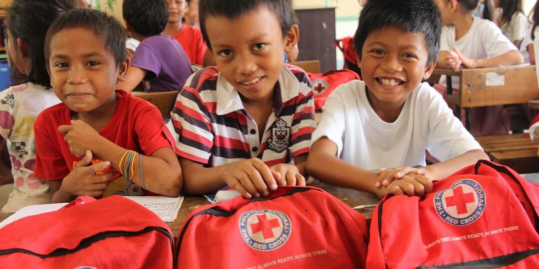 Tolosa, Leyte, Philippines9/3/2015Children from Tanghas Elementary School show off their new Red Cross backpacks. The students continue to enjoy their school, repaired with funds from the American Red Cross in 2014 in partnership with the Spanish Red Cross. Children received backpacks full of supplies to start the school year. The Red Cross installed hand water pumps, constructed six new latrines, and repaired classrooms that were badly damaged by Typhoon Haiyan. Even though it was ravaged by high winds and fallen coconut trees, about 20 families used the school as a shelter in the aftermath of the typhoon. One hundred and thirty-two students, from kindergarten to sixth grade, attend Tanghas Elementary School. The school’s five teachers all survived the storm and returned to teach this year. All the surrounding schools are full, so if this one wasn’t able to reopen, they’d have nowhere else to get their education. The Red Cross trains local people on carpentry, plumping, electrical and construction skills and then pays them to repair schools like Tanghas Elementary.“Without the Red Cross repairing the school, I don’t know what would happen to our children,” said school official, Noresita A. Go. This project is in collaboration with the Spanish Red Cross.
