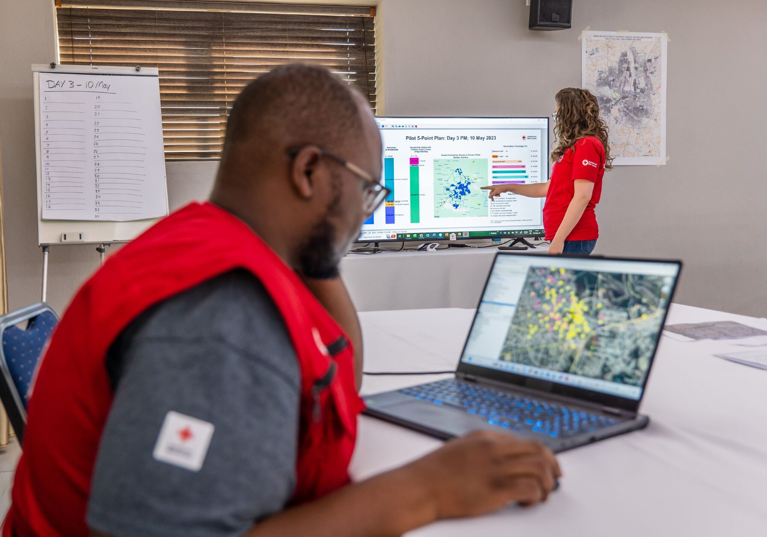 May 10, 2023. Kabwe, Zambia. Red Cross team members refer to maps and data from Kabwe, Zambia, as they plan door-to-door visits to identify un- and under-vaccinated children. Via a program sponsored by the American Red Cross and the Zambia Red Cross, teams visit parents in both rural villages and urban settlements to find pockets of children missing routine immunizationssuch as the measles vaccine. Some teams have to walk 40 minutes just to reach one house, while others ride bicycles and motorbikes down dusty, bumpy roads to locate kids in need. The program--called the 5-Point Plan--is done in conjunction with the Zambia Ministry of Health in order to gather the most up-to-date statistics to understand where and why some kids aren't getting vaccinated.  

The American Red Cross plays a pivotal role in supporting vaccination campaigns and strengthening routine immunization systems worldwide via the Measles &amp; Rubella Partnership (M&amp;RP). Activities include capacity building for local Red Cross and Red Crescent teams; mobilizing volunteers to spread word about the importance of immunizations via mass media, rallies, door-to-door visits and entertainment; and ensuring caregivers and kids get to health centers to obtain vaccines.  The Measles &amp; Rubella Partnership (previously named the Measles &amp; Rubella Initiative) was founded in 2001 by the American Red Cross, the UN Foundation, the U.S. Centers for Diseases Control and Prevention (CDC); UNICEF; and the World Health Organization; and has now been joined by the Bill &amp; Melinda Gates Foundation and GAVI, the Vaccine Alliance. Measles is one of the most contagious and severe childhood diseases. Every day, hundreds of childrens lives are lost around the globe from this preventable disease. Photo by Brad Zerivitz/American Red Cross