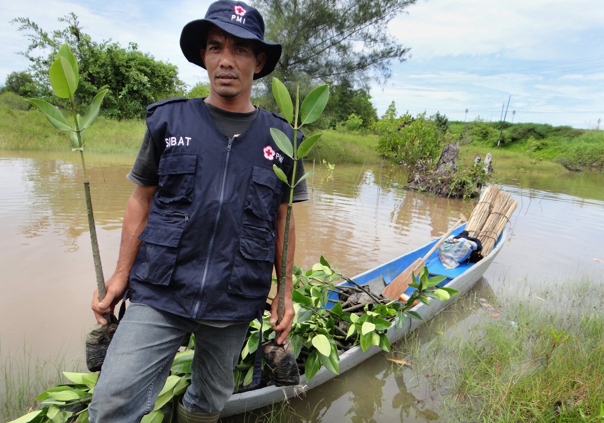 June 5, 2014. Aceh Jaya, Indonesia. A Red Cross volunteer loads his canoe full of mangrove saplings in preparation for planting. The American Red Cross is continuing to help villages, like this one in Indonesia, rebuild from the 2004 Indian Ocean Tsunami. By planting mangroves, the Red Cross is restoring an ecosystem that was severely damaged by the natural disaster. Mangroves not only slow down storm surges and slow erosion, but they also absorb three times as much carbon dioxide as other trees, dissolve heavy metals like mercury from the soil and water, and provide a habitat for shrimp and oysters. With the help of volunteers, the Red Cross is planting mangrove and casuarina trees throughout coastal areas of Indonesia. The American Red Cross provided relief in the immediate aftermath of the 2004 Indian Ocean Tsunami, but also invested in long-term projects to ensure that towns build back stronger, healthier, and better prepared for future disasters that may come their way. Photo by Jenelle Eli/American Red Cross