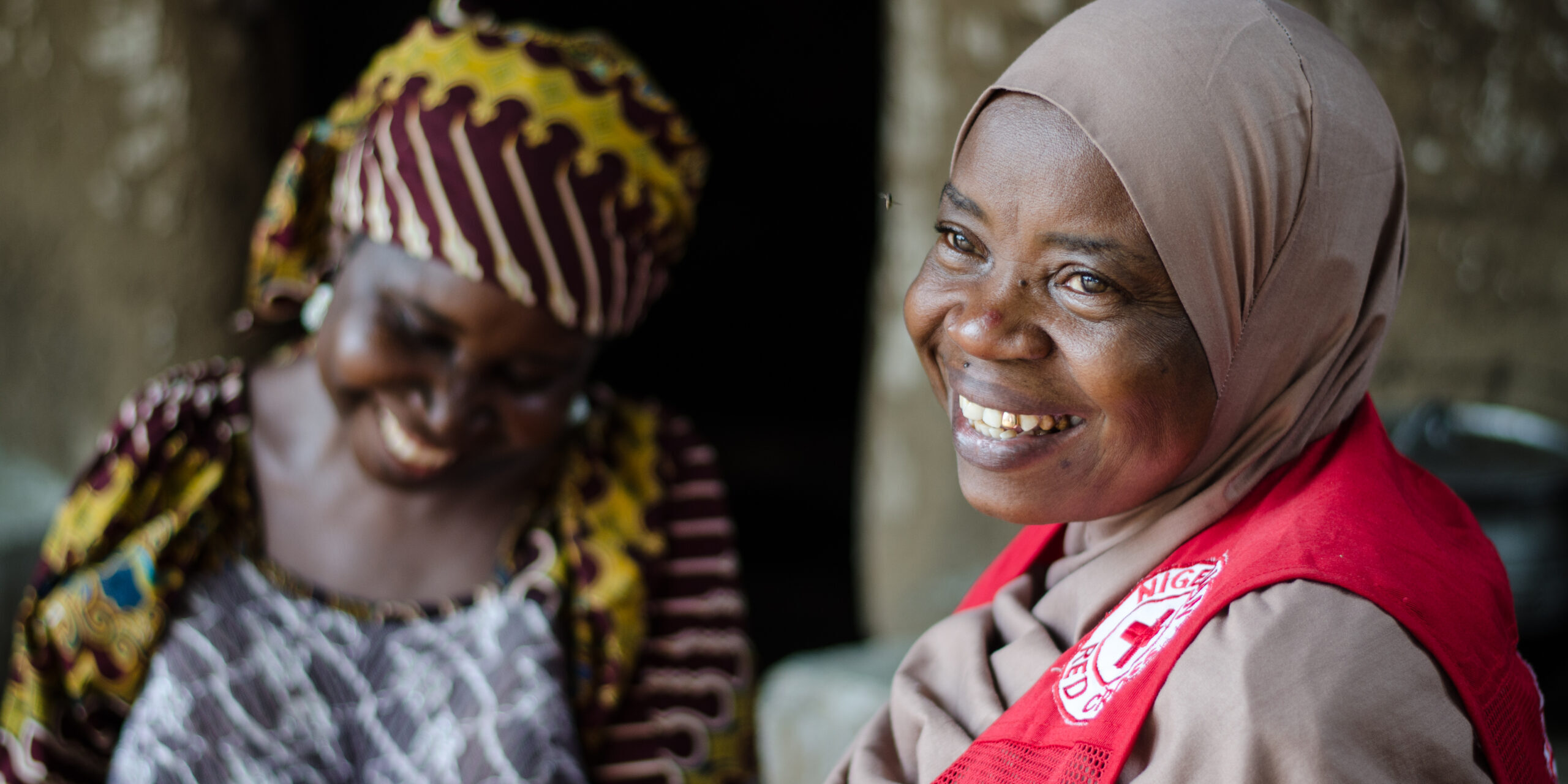 Hawa Magaji sits with Nigerian Red Cross divisional secretary of Song. During the armed conflict in north east Nigeria in 2014, Hawa`s community was attacked. She escaped with her family to safety. But just over a month later, she knew she needed to come back. 
On her returned, her goats and grains, including maize and groundnuts, were gone. With the help of the Nigerian Red Cross, Hawa has received enough money to invest back into her livelihood. She has bought seven goats, fertilizer for her farm and food to sustain her until her crops grow. She has also been able to renovate the foundations of her home where of her children reside.
The Red Cross is providing money for families, like Hawas, to enhance their ability to earn an income and feed their family. Cash has been distributed to people in Hong, Gombi and Song, allowing them to respond to their own unique needs and take charge of their recovery.
Smiling alone cannot express how happy I am, because I have never received any help like this in my life, says Hawa.
By the end of 2018, IFRC will support the Nigerian Red Cross in providing assistance to 360,000 people in three areas of Adamawa State (Gombi, Hong and Song) with food, shelter, sanitation and hygiene, community health services, cash and livelihoods projects.